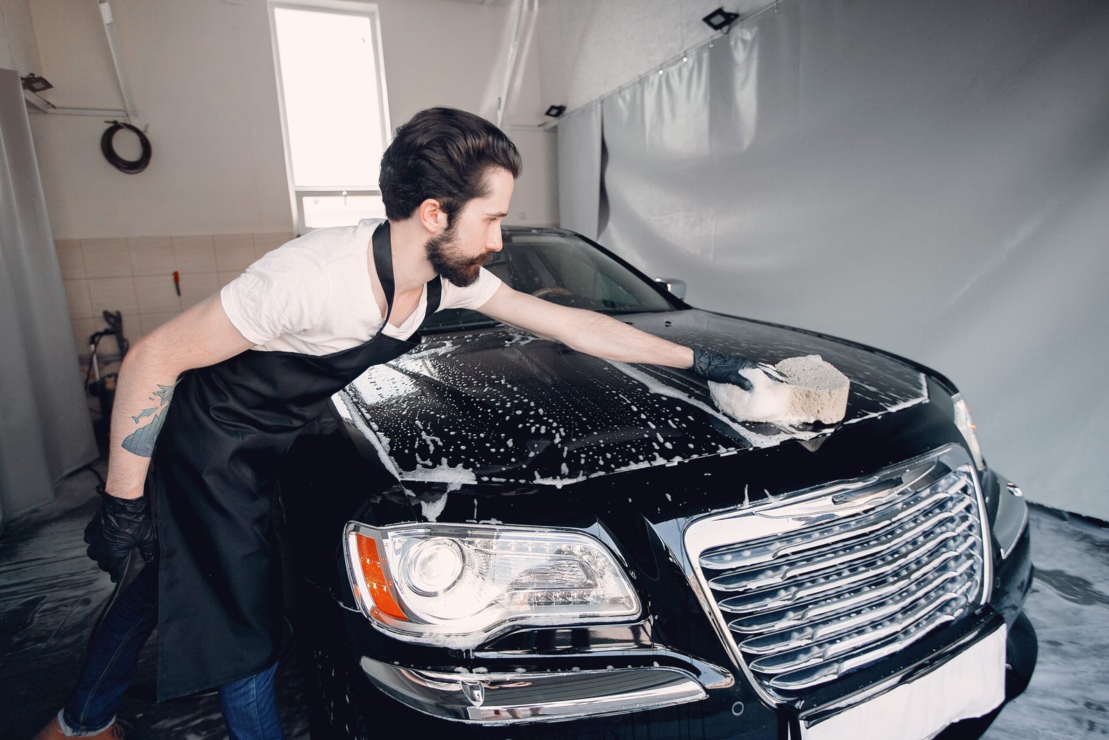 Man in a garage. Worker washing a car.